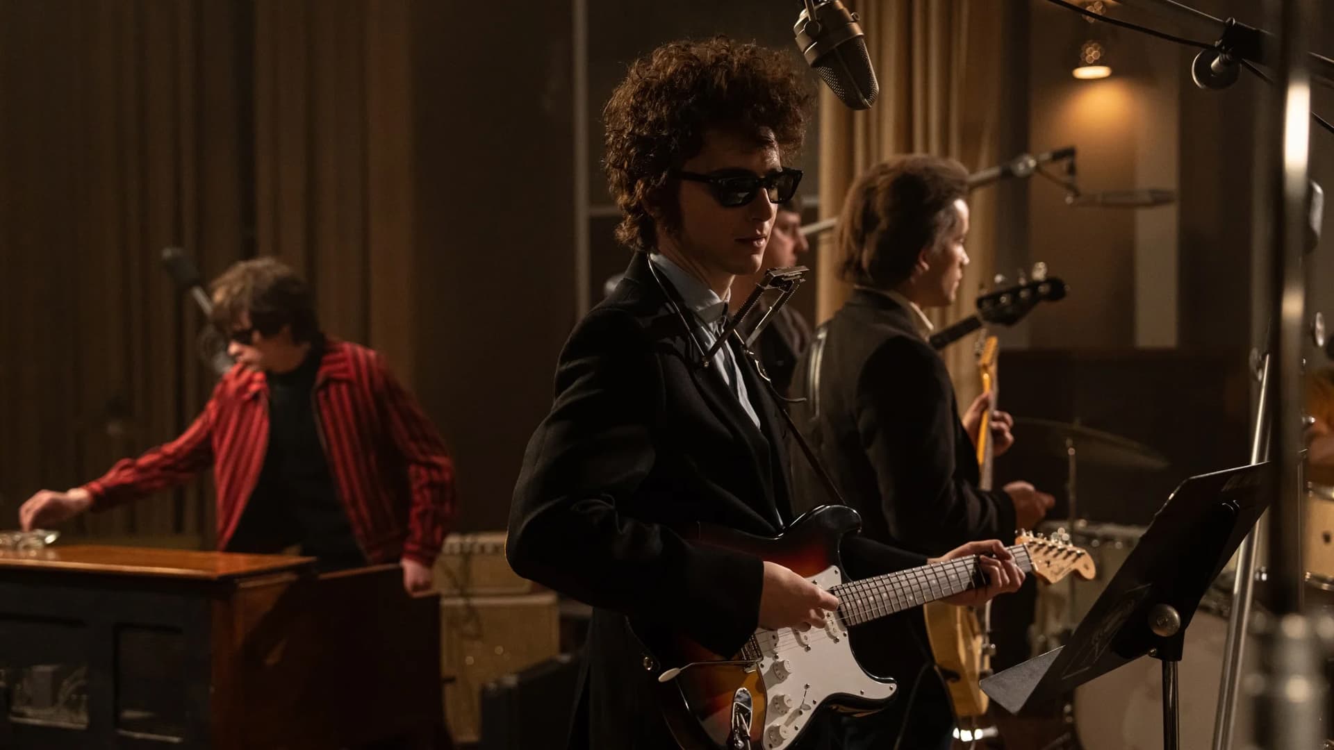 Still from A Complete Unknown. Timothée Chalamet, as Bob Dylan, in the studio with his guitar.